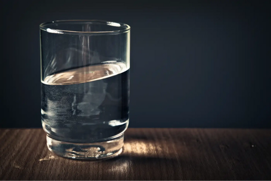 Verre d'eau transparent sur une table en bois foncé