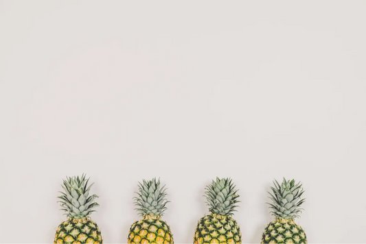 photo de quatre ananas devant un mur clair